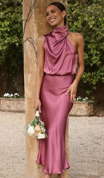 Woman wearing a pink satin halter midi dress holding a bouquet