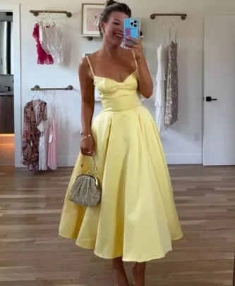 Woman wearing a yellow satin midi dress with spaghetti straps