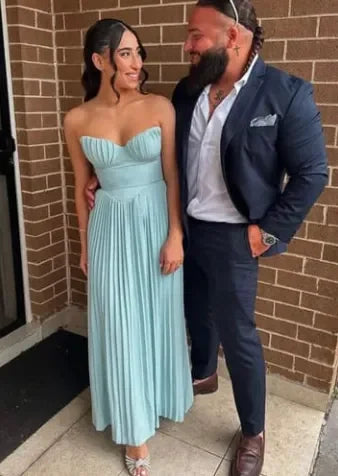 Woman in a light blue pleated bustier maxi dress next to a man in a navy suit