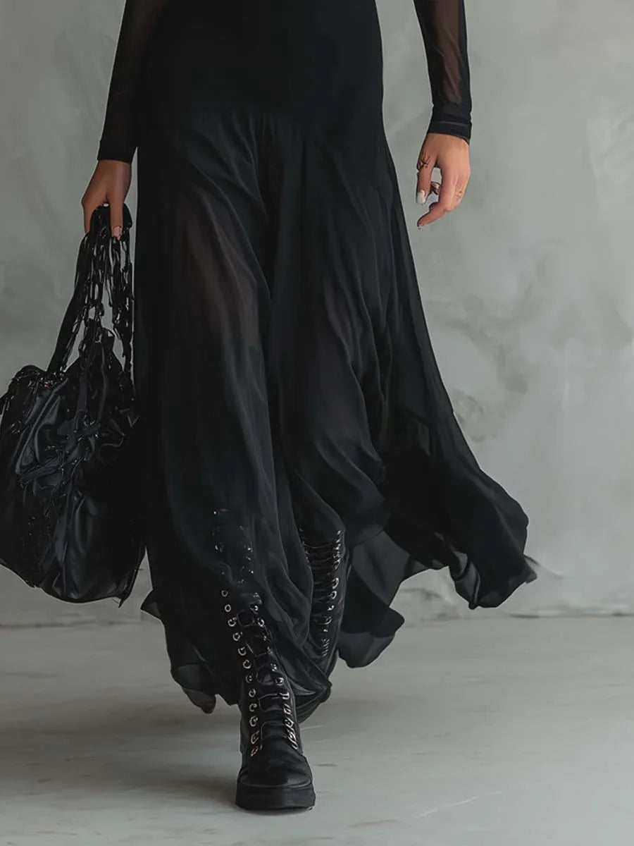 Women's black maxi dress with sheer layers and long sleeves, skirt in motion