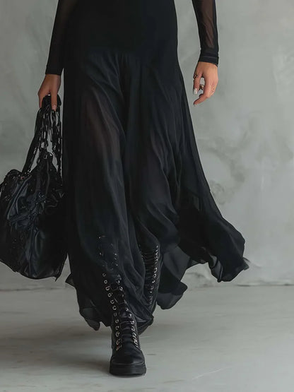Women's black maxi dress with sheer layers and long sleeves, skirt in motion