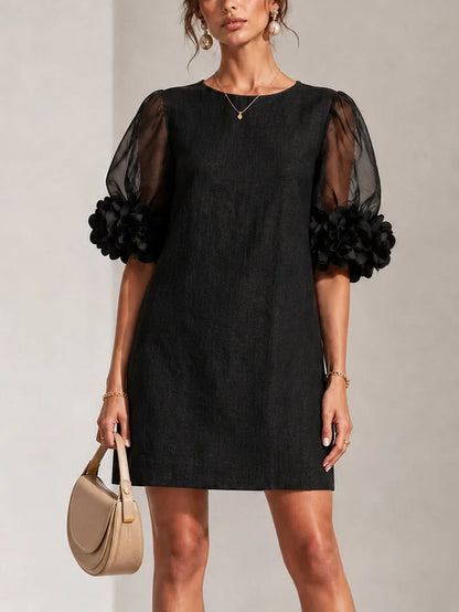 Women's black puff-sleeve mini dress with floral rose cuffs, front view with handbag