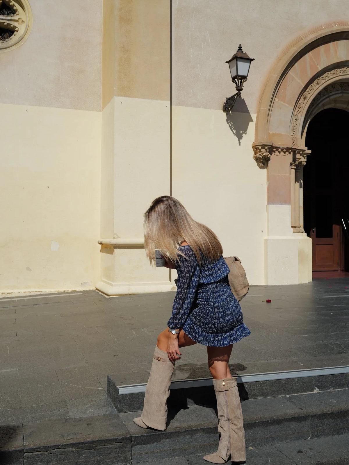 Women's fold-over knee-high boots with gold buckle, beige, worn on the steps