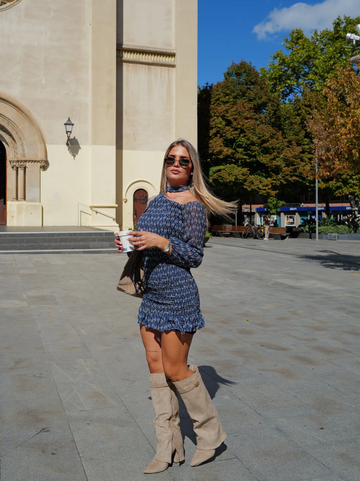 Women's fold-over knee-high boots with gold buckle, beige, worn with a patterned mini dress