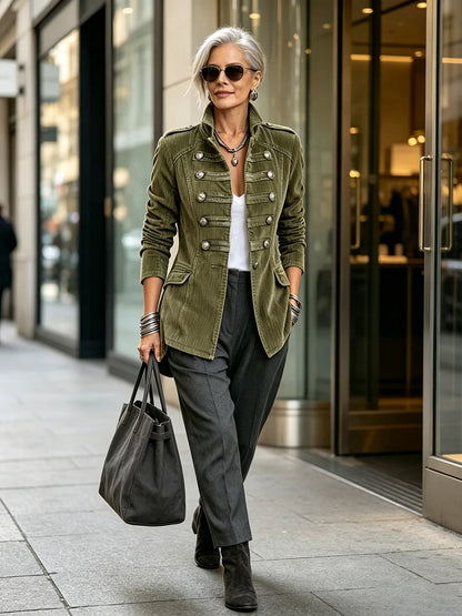 Women's olive military-style jacket with double row of metal buttons, styled with a tote bag outdoors