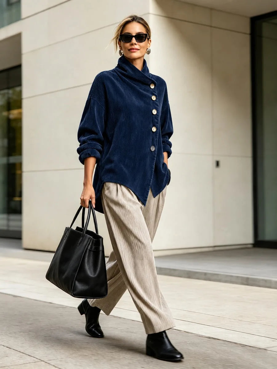 Women's navy high-collar jacket with diagonal buttons, styled with wide-leg trousers and a tote bag