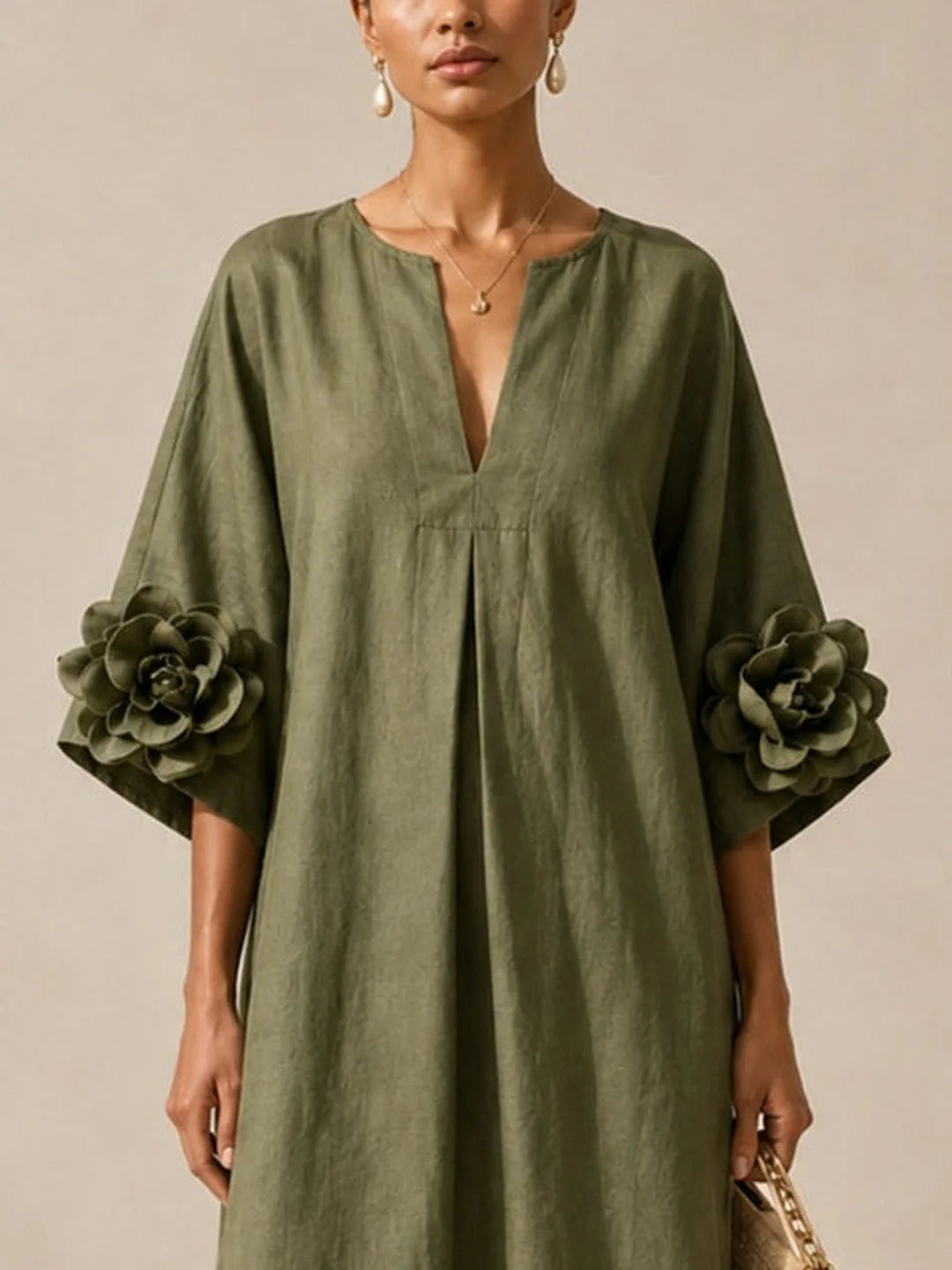 Women's olive green midi dress with floral appliqué sleeves, close-up of the V-neckline and floral sleeve detail