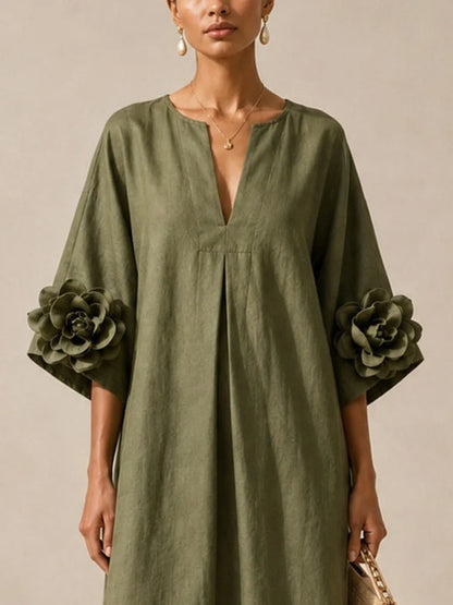 Women's olive green midi dress with floral appliqué sleeves, close-up of the V-neckline and floral sleeve detail