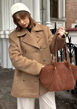 Women's oversized double-breasted camel coat with lapels, styled with a tote bag